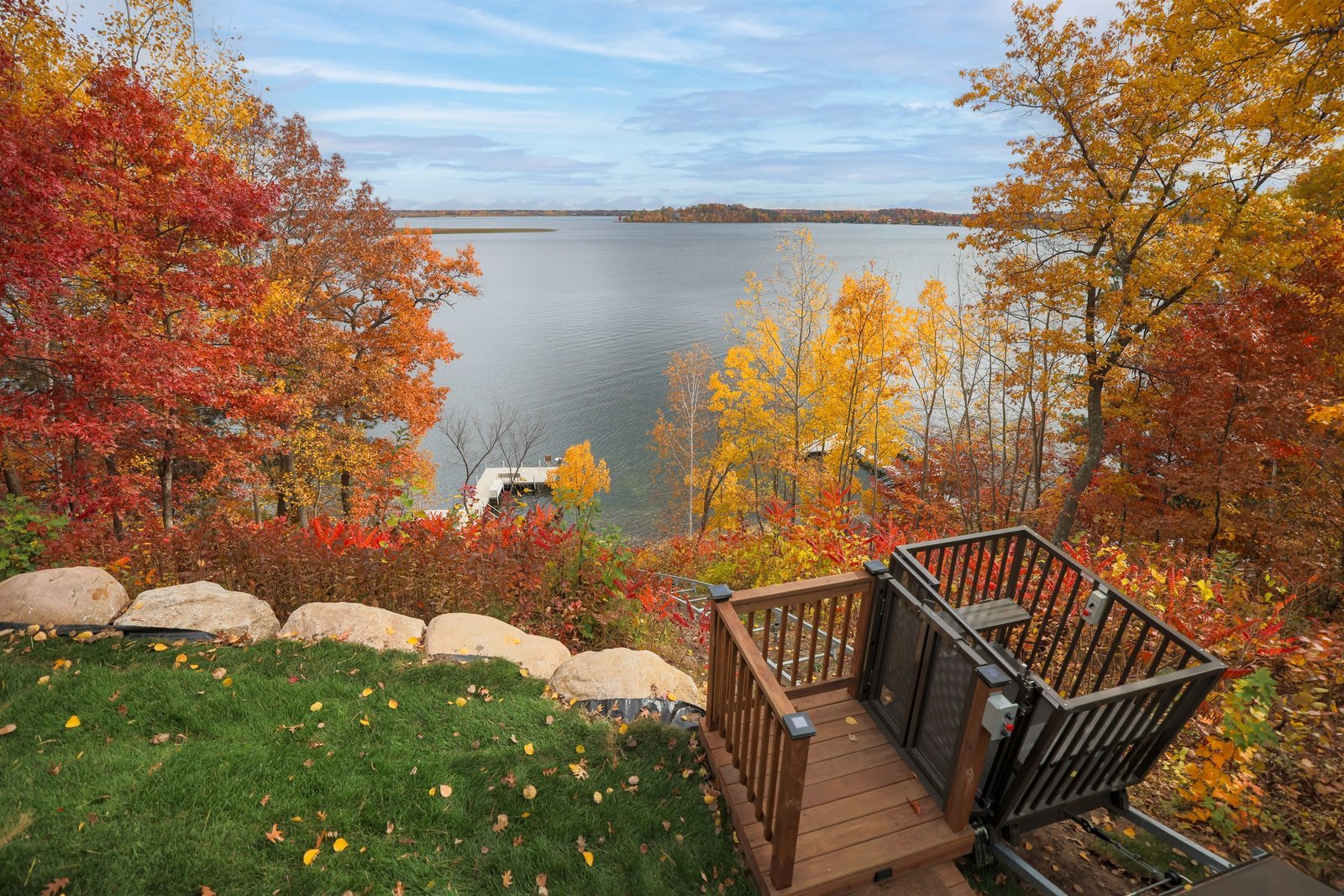 Autumn trees in bright red and gold frame a wooden deck above a Minnesota lake.